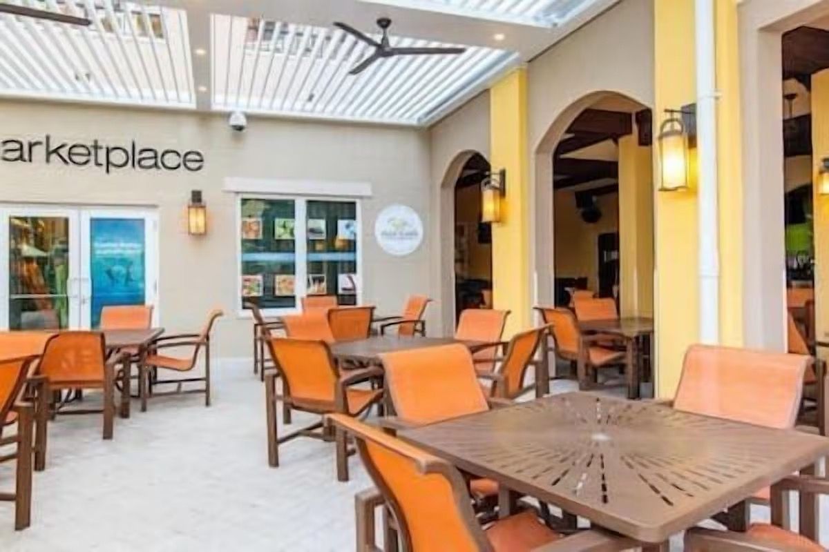 Un restaurant avec une terrasse, une enseigne indiquant « marché » et un ventilateur de plafond.