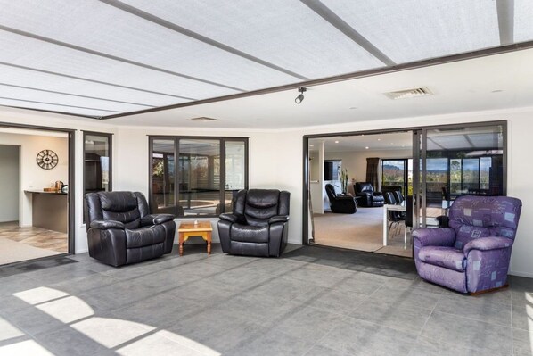 A spacious living area with a large sliding glass door leading to a balcony, leather sofas, and a small wooden table.