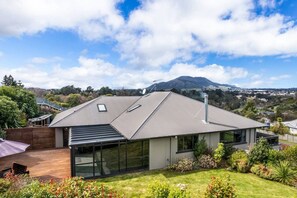 A modern house with a sloped roof, large windows, and a view of a mountain.