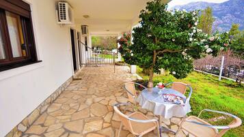A covered outdoor area with stone flooring, wicker furniture, and a table with a magazine.