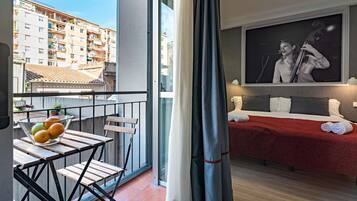 Een balkon met een tafel, stoelen en een schaal fruit.
