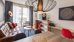 A modern living room with a leather sofa, a dining table, and a red chair. - Hot Jazz 51 (Barcelona)