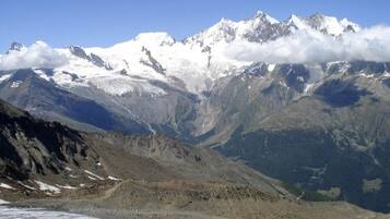 A mountainous landscape with snow-capped peaks, a valley, and a glacier.