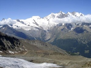 Eine gebirgige Landschaft mit schneebedeckten Gipfeln, einem Tal und einem Gletscher.