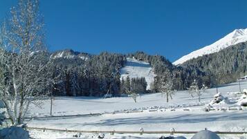 Schneebedeckte Landschaft mit einem Berg im Hintergrund und blauem Himmel.