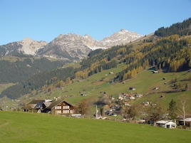 Paisaje rural con un pueblo, campos verdes y montañas al fondo.