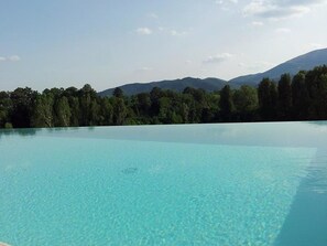 A clear blue pool with a view of a forested mountain range. - Collina - One Bedroom (Perugia)