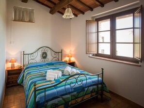 A bedroom with a bed, two bedside lamps, a window, and a hanging light fixture. - Collina - One Bedroom (Perugia)