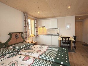 A room with a bed, a desk, and a kitchenette. - Mutthorn - One Bedroom (Lauenen)