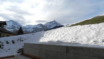 Schneebedeckte Landschaft mit Bergen im Hintergrund und einer Betonkonstruktion im Vordergrund.