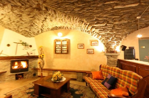 Una sala de estar acogedora con techo de piedra, chimenea, sofá y mesa de centro.