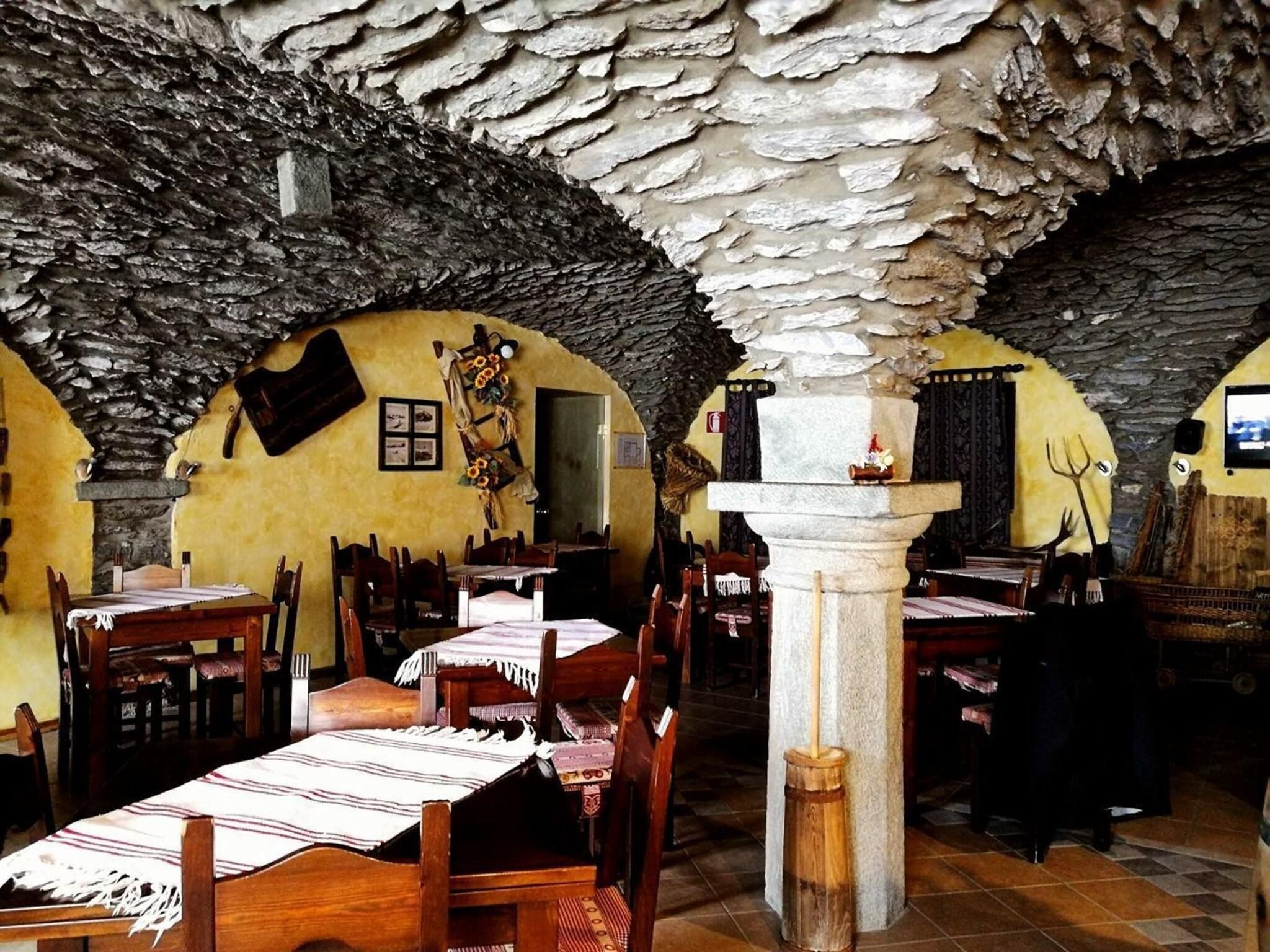 Ein rustikales Interieur mit Steinwänden, Holztischen und -stühlen.