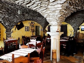 Un interior rústico con paredes de piedra, mesas y sillas de madera.
