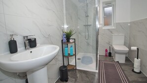 Un bagno moderno con lavandino bianco, WC e cabina doccia in vetro.