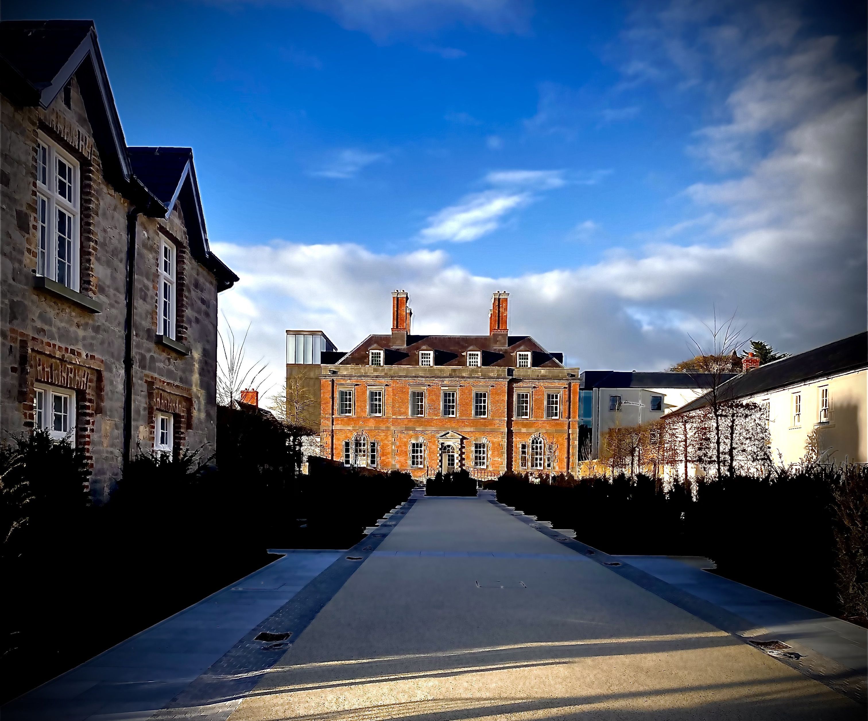A long, straight pathway leading to a large, multi-story building with a symmetrical facade and a central entrance.
