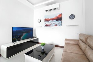 A modern living room with a flat-screen TV, a coffee table with a clock, a sofa, and two wall-mounted clocks. - Elyana -Serene 3BR Pool Villa Retreat (Tambon Rawai)