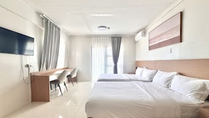 A hotel room with two beds, a desk, and a TV. - Royal Oceancrest Panglao 1 (Dauis)