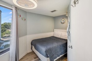A bedroom with a bed, a window with curtains, a ceiling fan, and a view of the outside. - Breathtaking Ocean Views Your Beachside Getaway (Myrtle Beach)