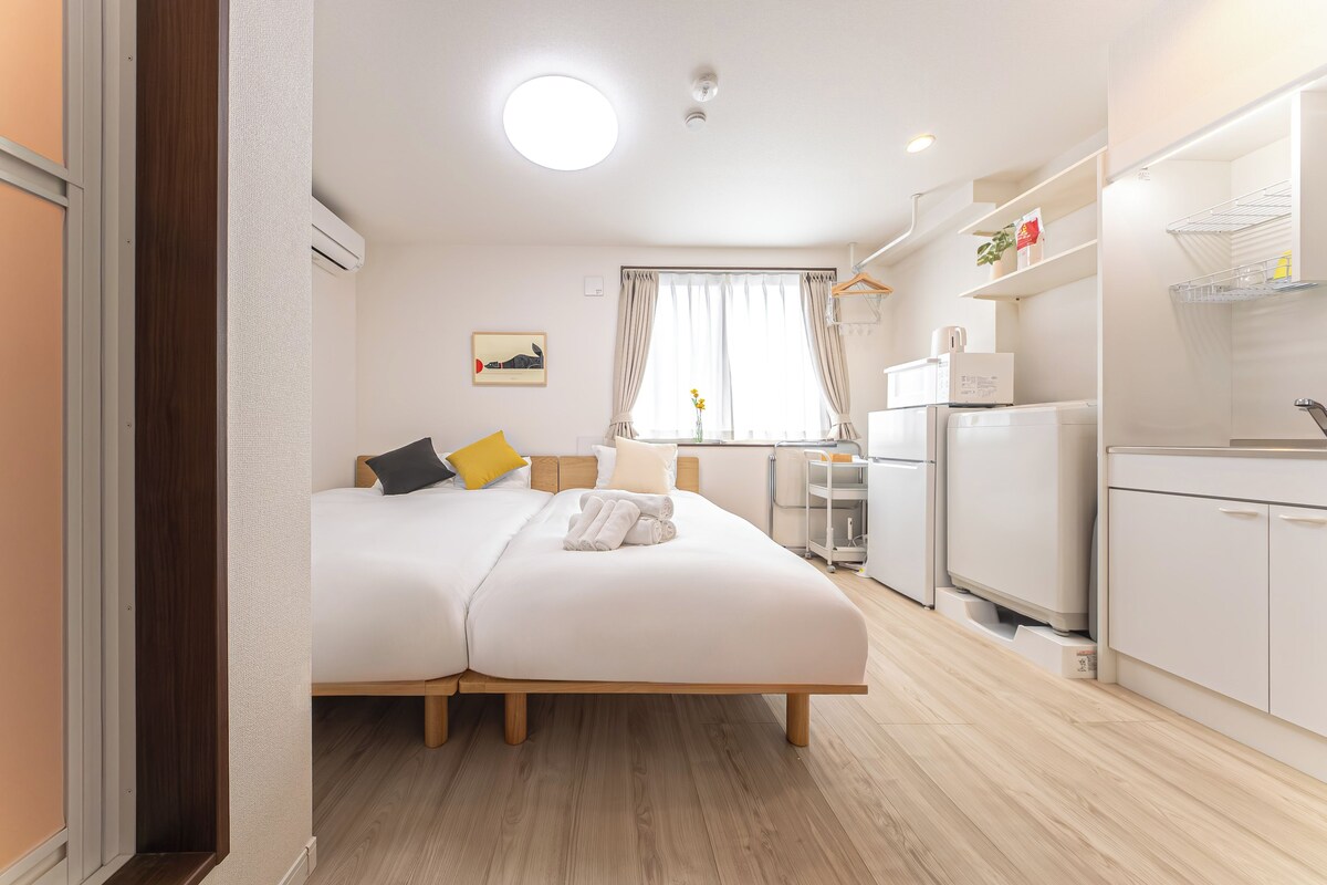 Ein Hotelzimmer mit einem Bett, einer kleinen Küchenzeile und einem fenster mit Vorhängen.