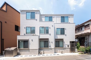Ein mehrstöckiges Wohngebäude mit flacher Fassade, zahlreichen Fenstern und Klimaanlagen.
