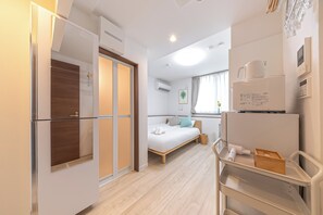 Ein Hotelzimmer mit Bett, Schreibtisch, Stuhl, Kleiderschrank und einer Küchenzeile.