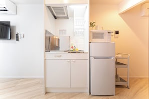 Eine kompakte Küche mit Kühlschrank, Mikrowelle und kleinem Spülbecken.
