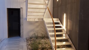 A modern staircase with wooden handrails and a tiled floor leading to a dark doorway. - Malaga City Breaks (Málaga)