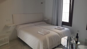 A hotel room with a bed, bedside table, and a glass table with a remote control and wine bottle. - Malaga City Breaks (Málaga)