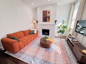 Un salon avec un canapé, une cheminée, une table basse et un téléviseur.