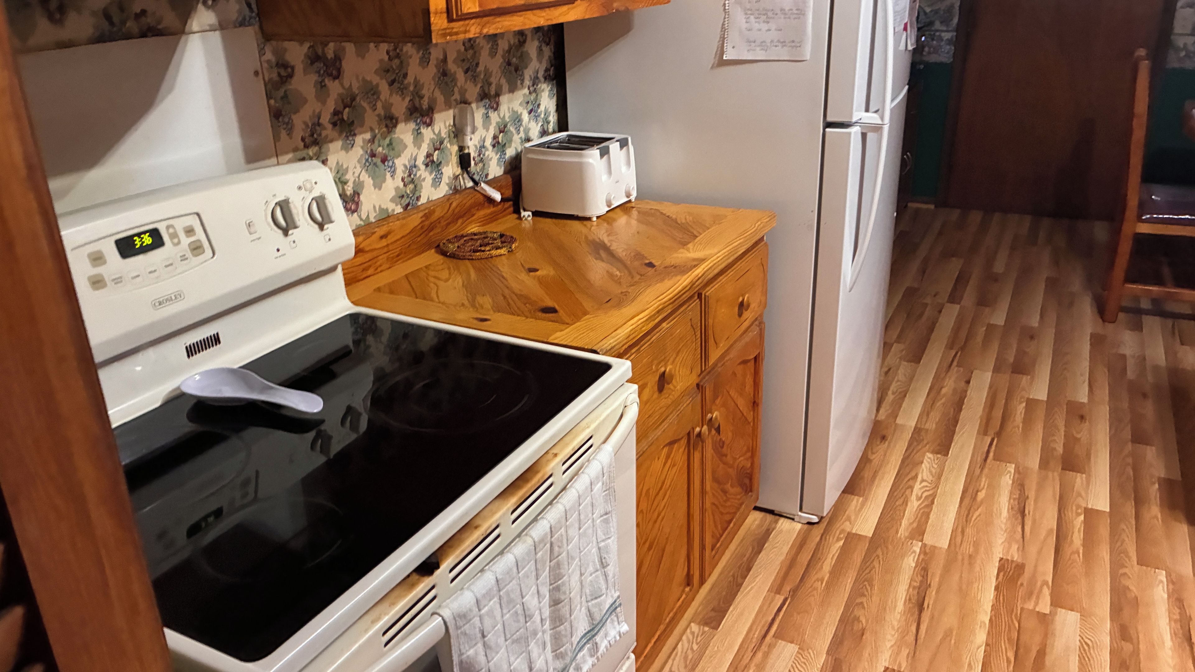 A kitchen with a white stove, a toaster, and a refrigerator.