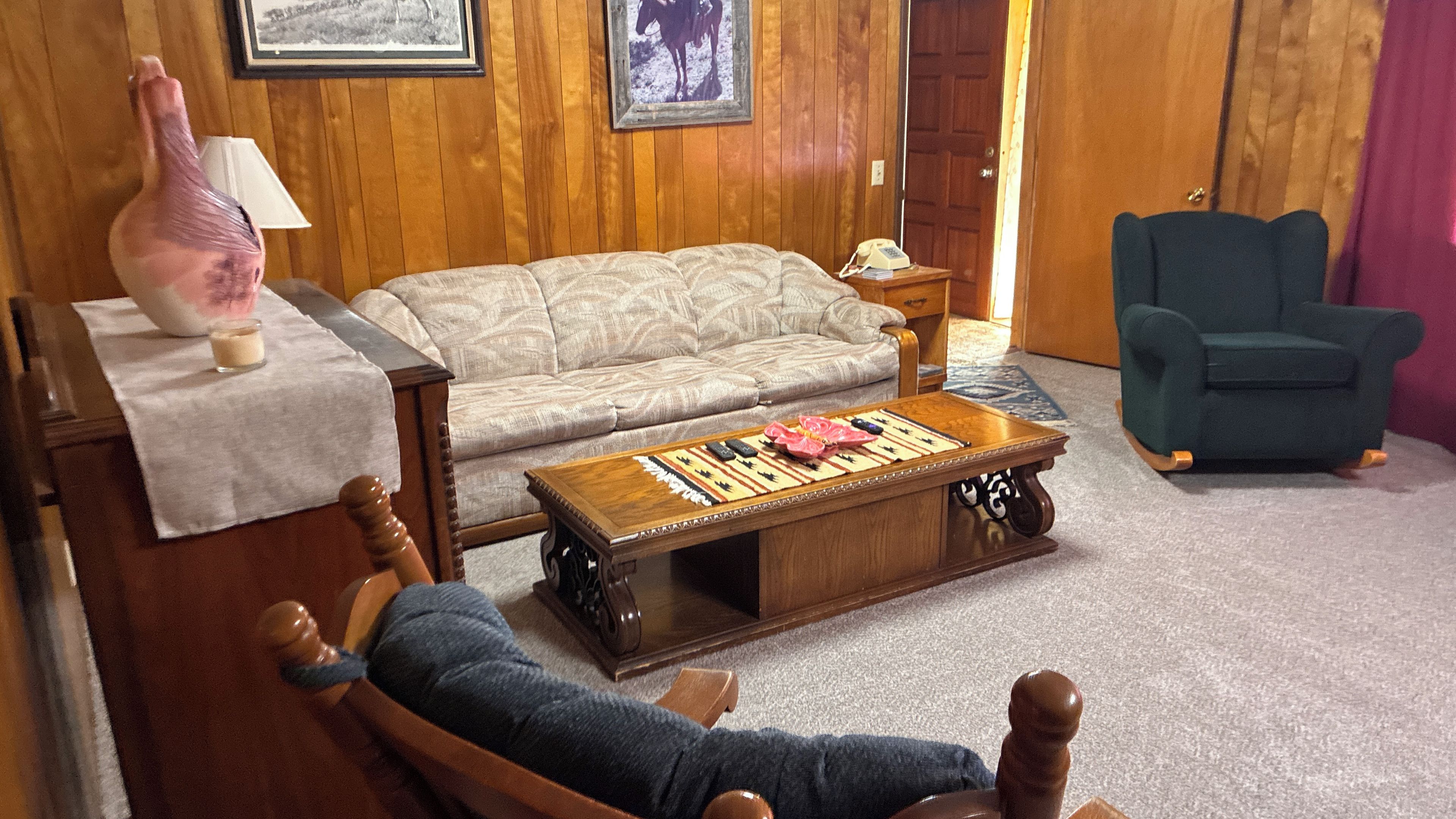 A living room with a sofa, a coffee table with a board game, a chair, and a lamp.