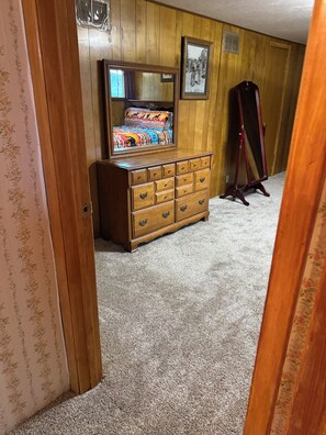 A room with a wooden dresser, a mirror, and a framed picture on the wall.