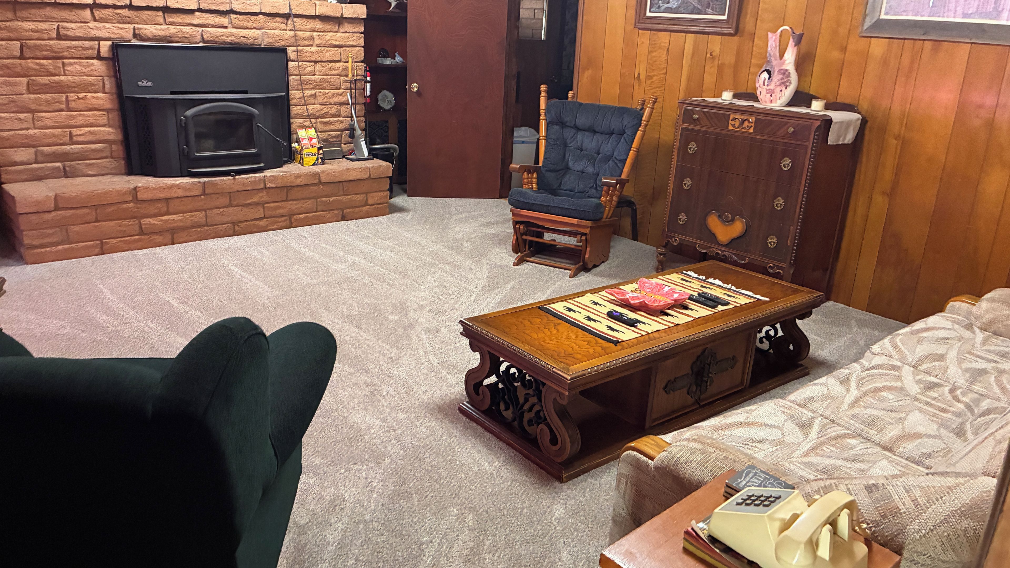 A living room with a fireplace, a wooden coffee table, a sofa, and a chair.