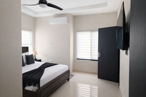 A bedroom with a bed, a ceiling fan, a TV mounted on the wall, and a window with blinds. - Spacious 3-bedroom house in wonderful Ocho Rios with AC and infinity pool. (Ocho Rios)