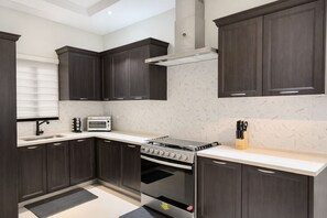 A modern kitchen with dark wood cabinets, a built-in oven, a gas stove, and a microwave. - Spacious 3-bedroom house in wonderful Ocho Rios with AC and infinity pool. (Ocho Rios)