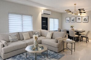 A modern living room with a sofa, coffee table, and dining area. - Spacious 3-bedroom house in wonderful Ocho Rios with AC and infinity pool. (Ocho Rios)