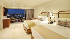 Une chambre d’hôtel avec deux lits, un bureau et une vue sur le paysage urbain.