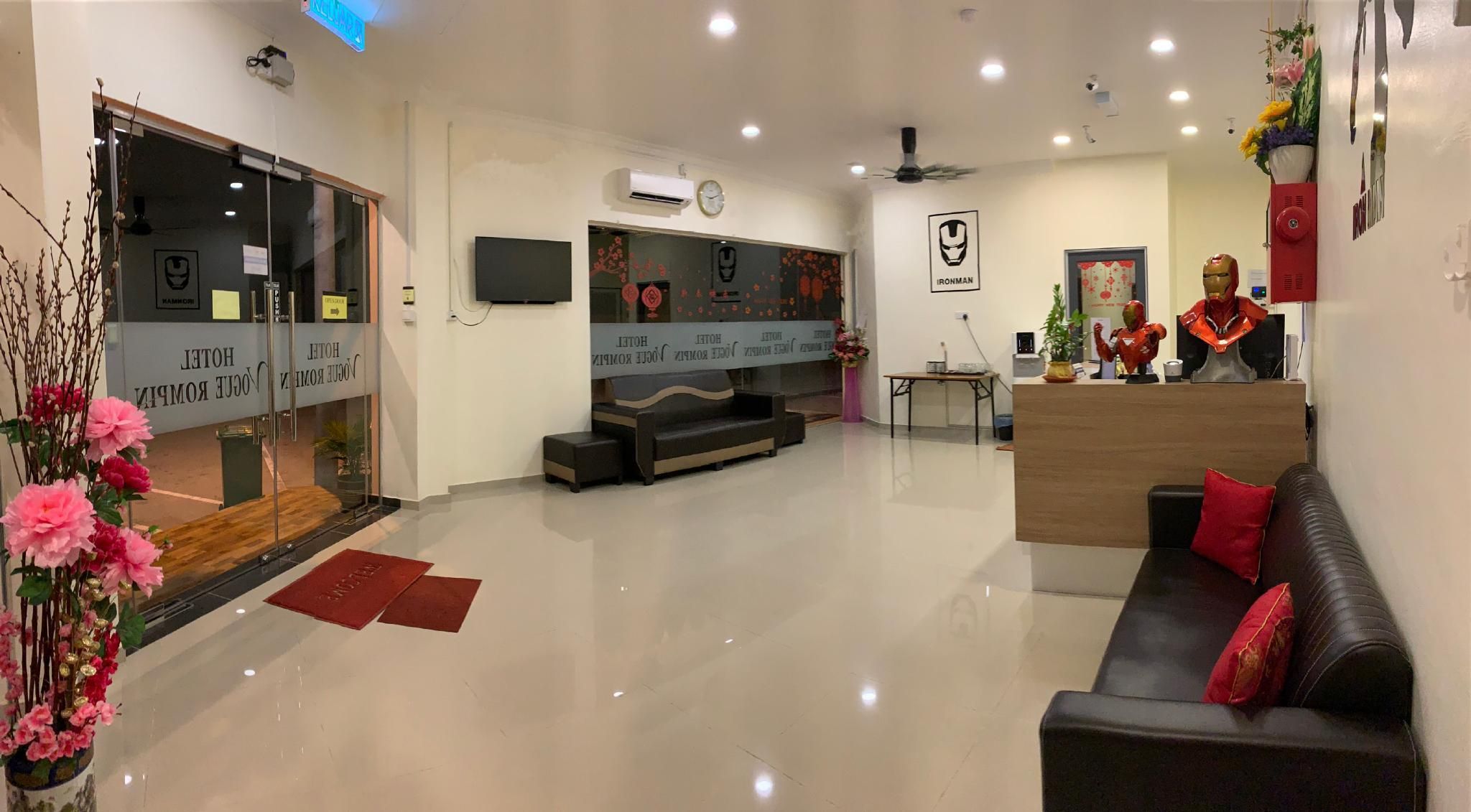 A hotel lobby with a reception desk, seating area, and a large flat-screen TV.