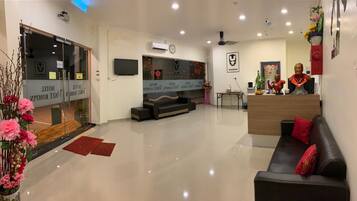 A hotel lobby with a reception desk, seating area, and a large flat-screen TV.