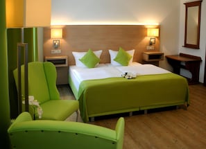 A hotel room with a bed, two nightstands, a chair, and a mirror. - Parkhotel-forsthaus Dresden (Tharandt)