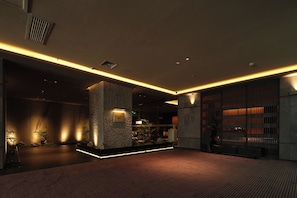 A modern interior with a stone pillar, a reception desk, and a bookshelf. - YOMANJO (Guangzhou)
