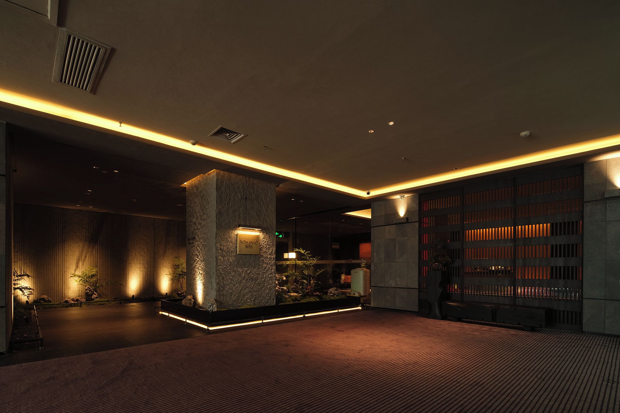 A modern interior with a stone pillar, a reception desk, and a bookshelf.