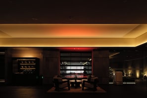 A dimly lit room with a seating area, a bookshelf, and a large window. - YOMANJO (Guangzhou)