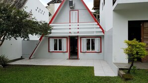 Een huis met een flauw aflopende, rode luiken en witte buitenmuren.