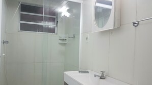 Een badkamer met een douche, wastafel en spiegel.