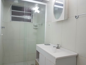Une salle de bain avec une douche, un lavabo et un miroir.