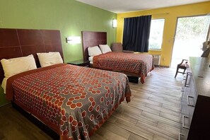 Una habitación de hotel con dos camas, un escritorio y vistas al exterior.