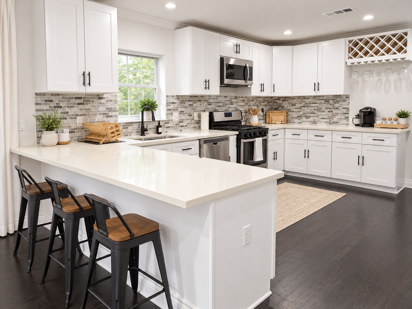 A modern kitchen with white cabinetry, a large island with bar stools, a microwave, stove, and a sink.