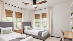 Habitación de hotel con dos camas, un escritorio y un ventilador de techo.
