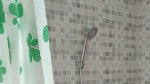 Suihkussa on käsisuihkupää ja seinään asennettu hana.